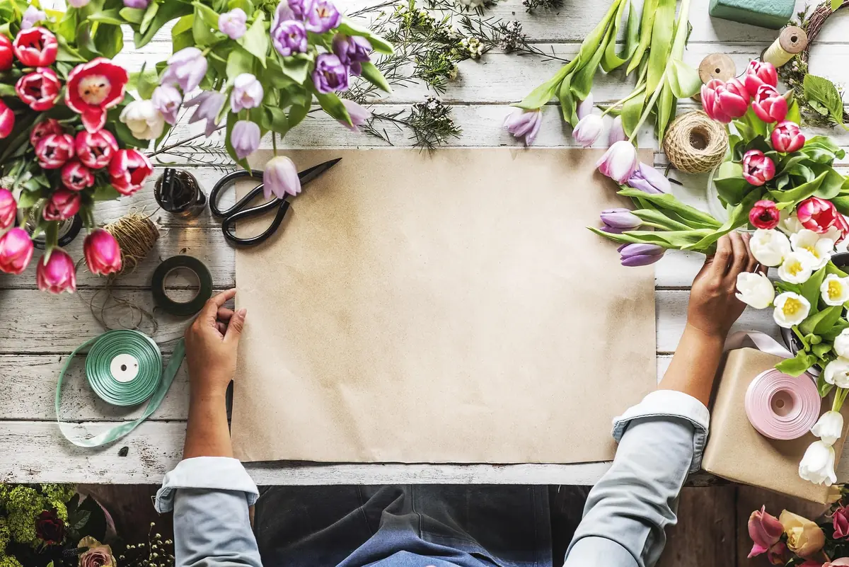 Plan de travail de fleuriste avec tulipes, ciseaux, rubans et papier kraft