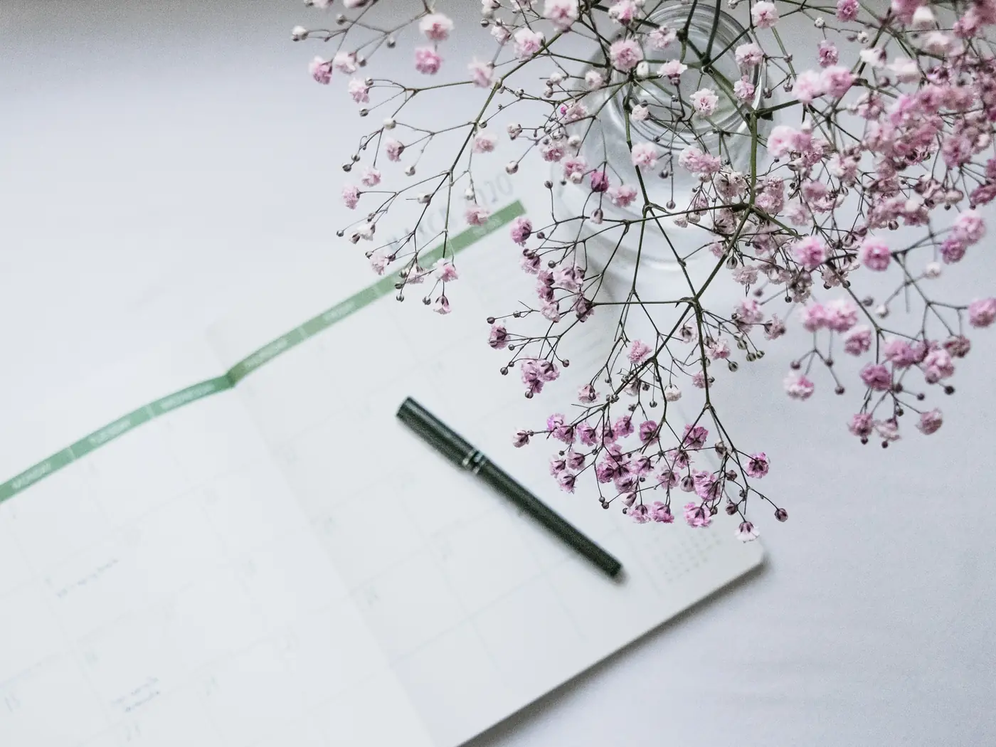 Agenda ouvert posé à côté d’un bouquet de gypsophile rose