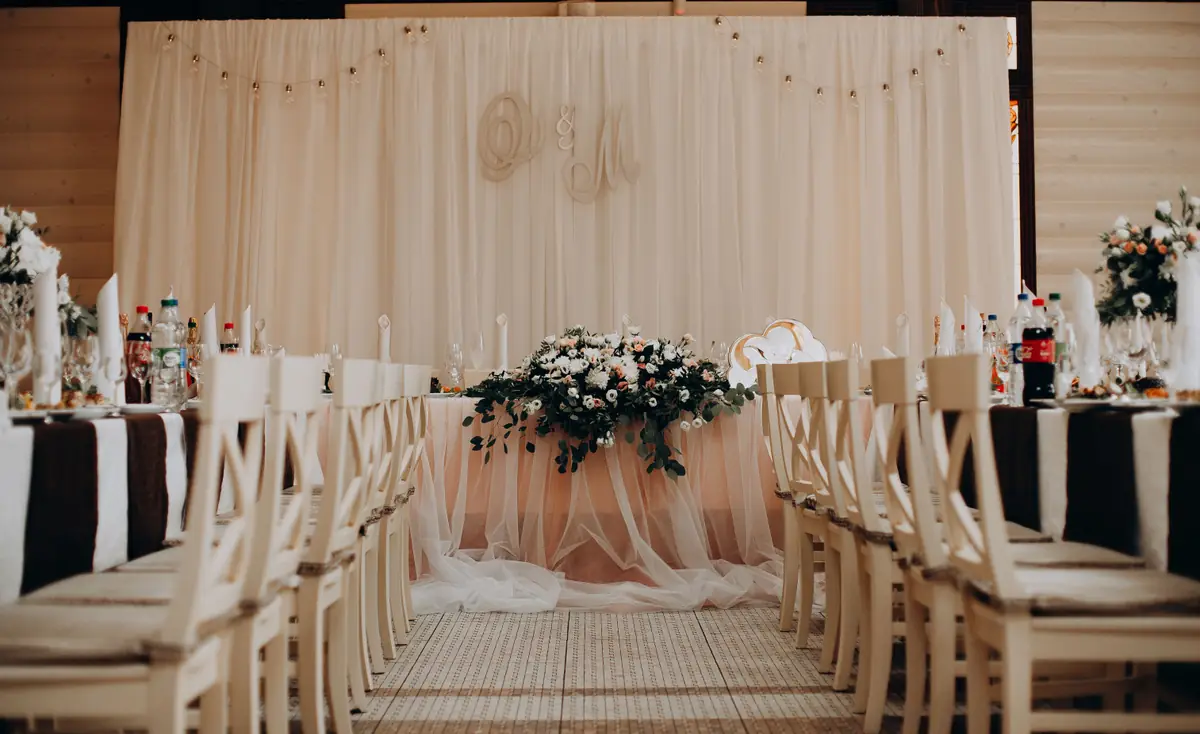 Table d’honneur dressée devant un décor de tulle dans une salle de mariage